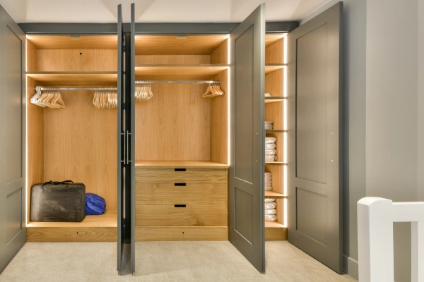 a walk in closet with wooden shelves and black doors